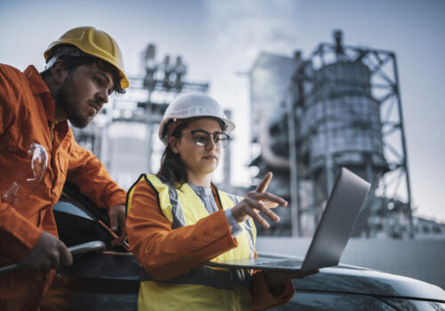 Two engineers man and woman using laptop to work at power plant on night shift.